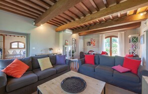 Un salon avec un plafond en bois, deux canapés avec des coussins, une table basse et un coin repas avec des chaises.