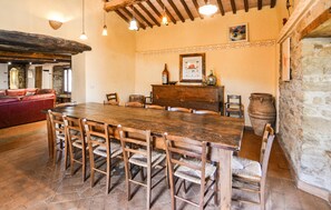 A rustic dining area with a wooden table and chairs, a stone wall, and a fireplace. - Nice home in Caprese Michelangelo (Caprese Michelangelo)