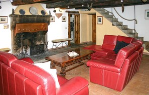A living room with red leather sofas, a wooden coffee table, and a fireplace. - Nice home in Caprese Michelangelo (Caprese Michelangelo)