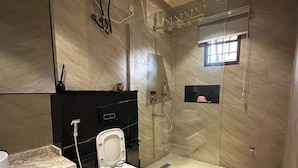 Un baño moderno con ducha de mampara de vidrio, inodoro, lavamanos y espejo.