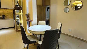 Un comedor moderno con una mesa redonda y cuatro sillas, una cocina con nevera empotrada y una pared con tres espejos redondos.