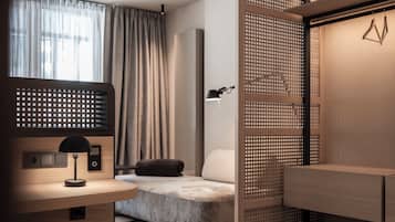 Un dormitorio moderno con una cama, un escritorio con lámpara, una luz de pared y una ventana con cortinas.