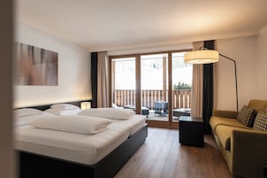 Una habitación de hotel con cama, sofá, una mesita y un balcón con vistas al exterior.