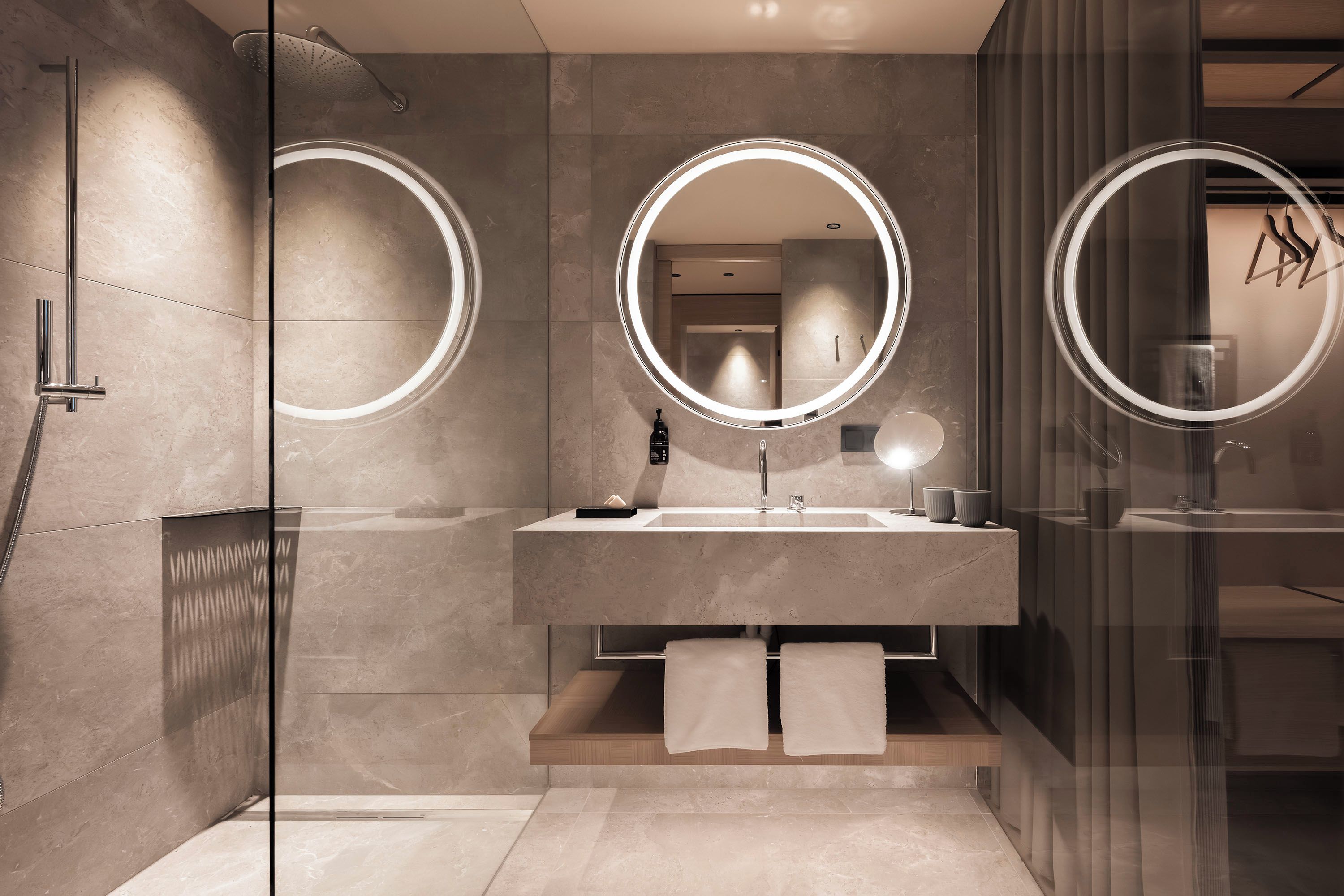 A modern bathroom with a glass shower enclosure, a vanity with a mirror, and a towel rack.