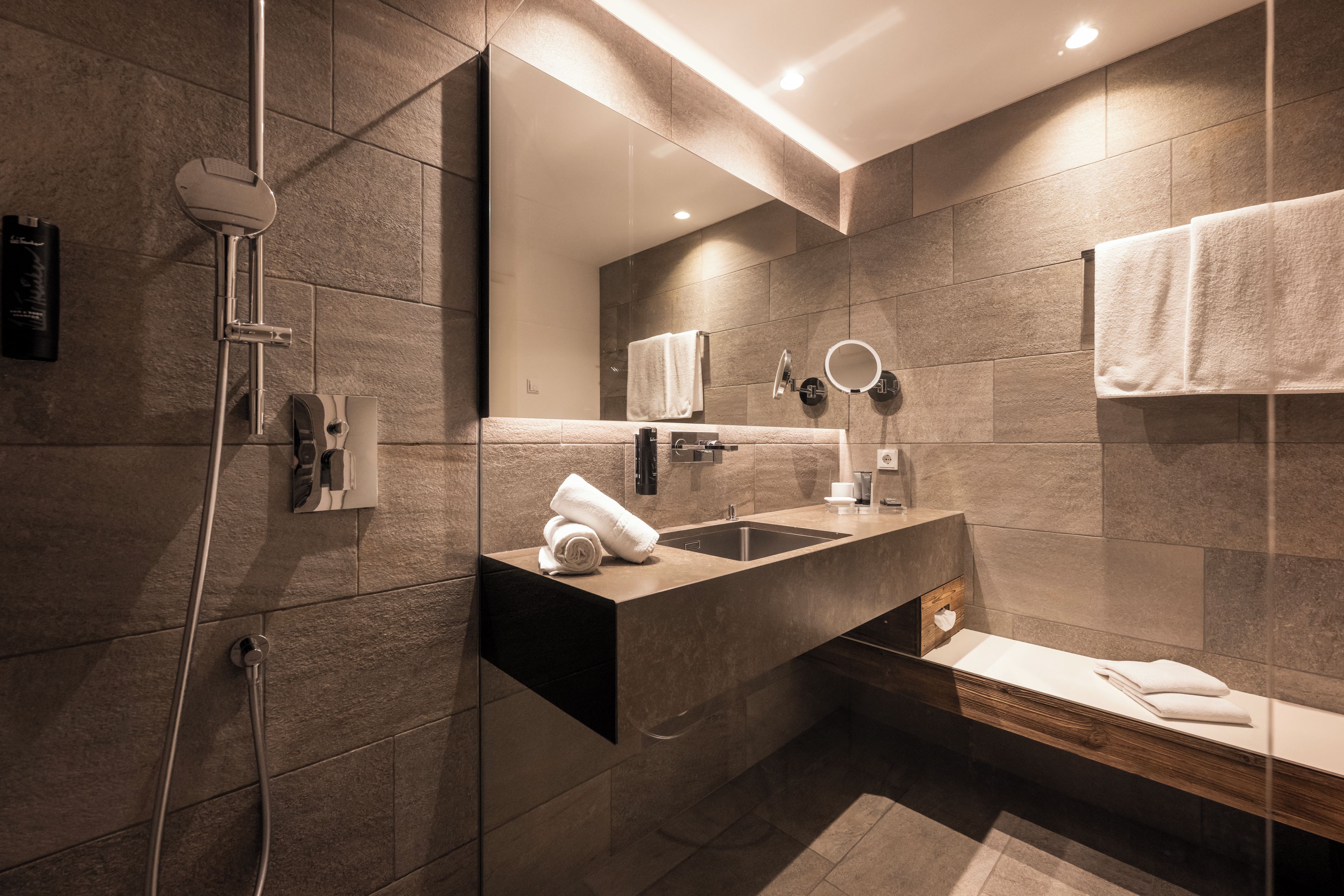 A modern bathroom with a built-in sink, a mirror, a towel rack, and a shower area.