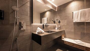 A modern bathroom with a built-in sink, a mirror, a towel rack, and a shower area.