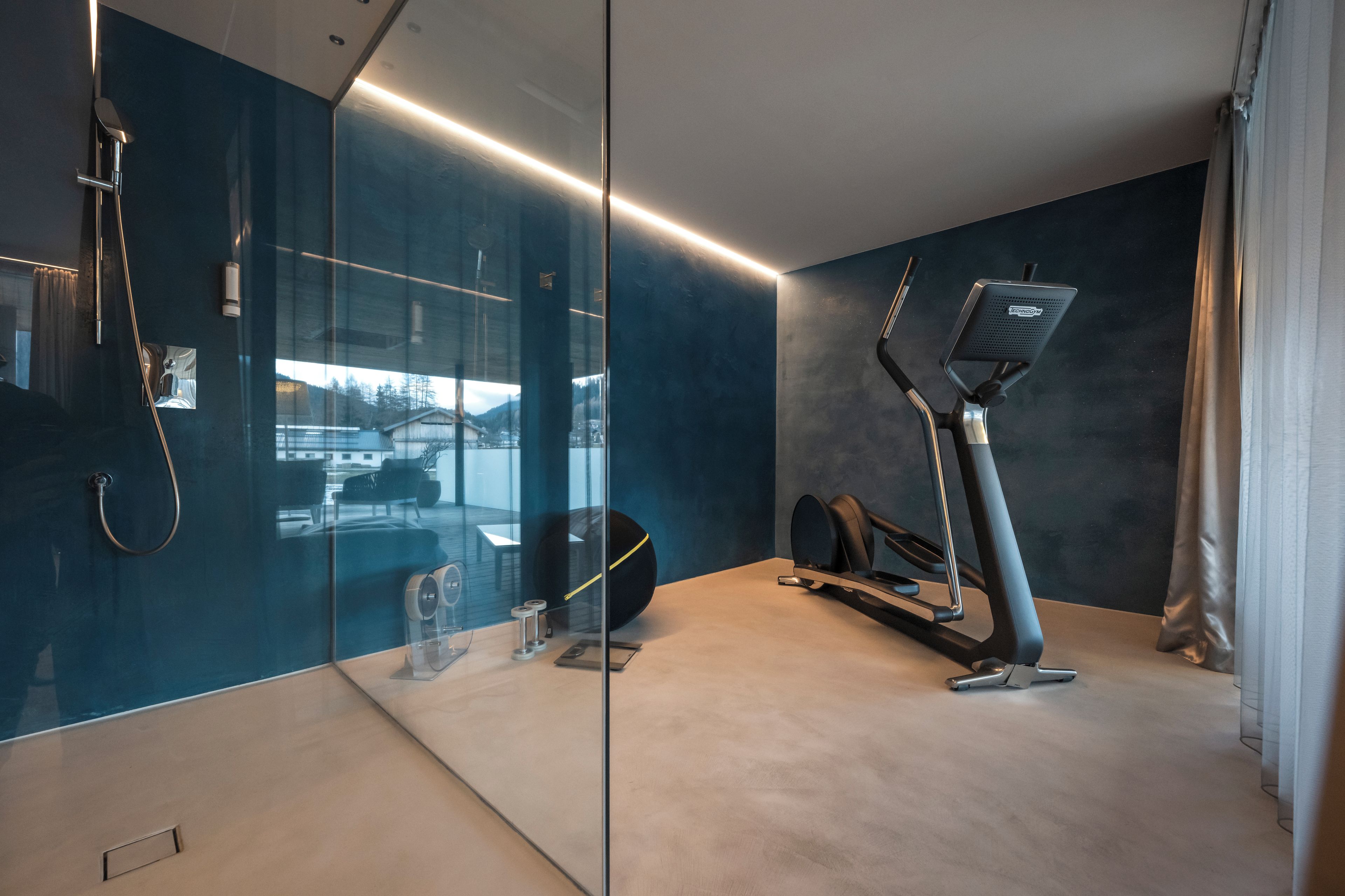 Un baño moderno con mampara de vidrio, ducha, inodoro y una cinta de correr.