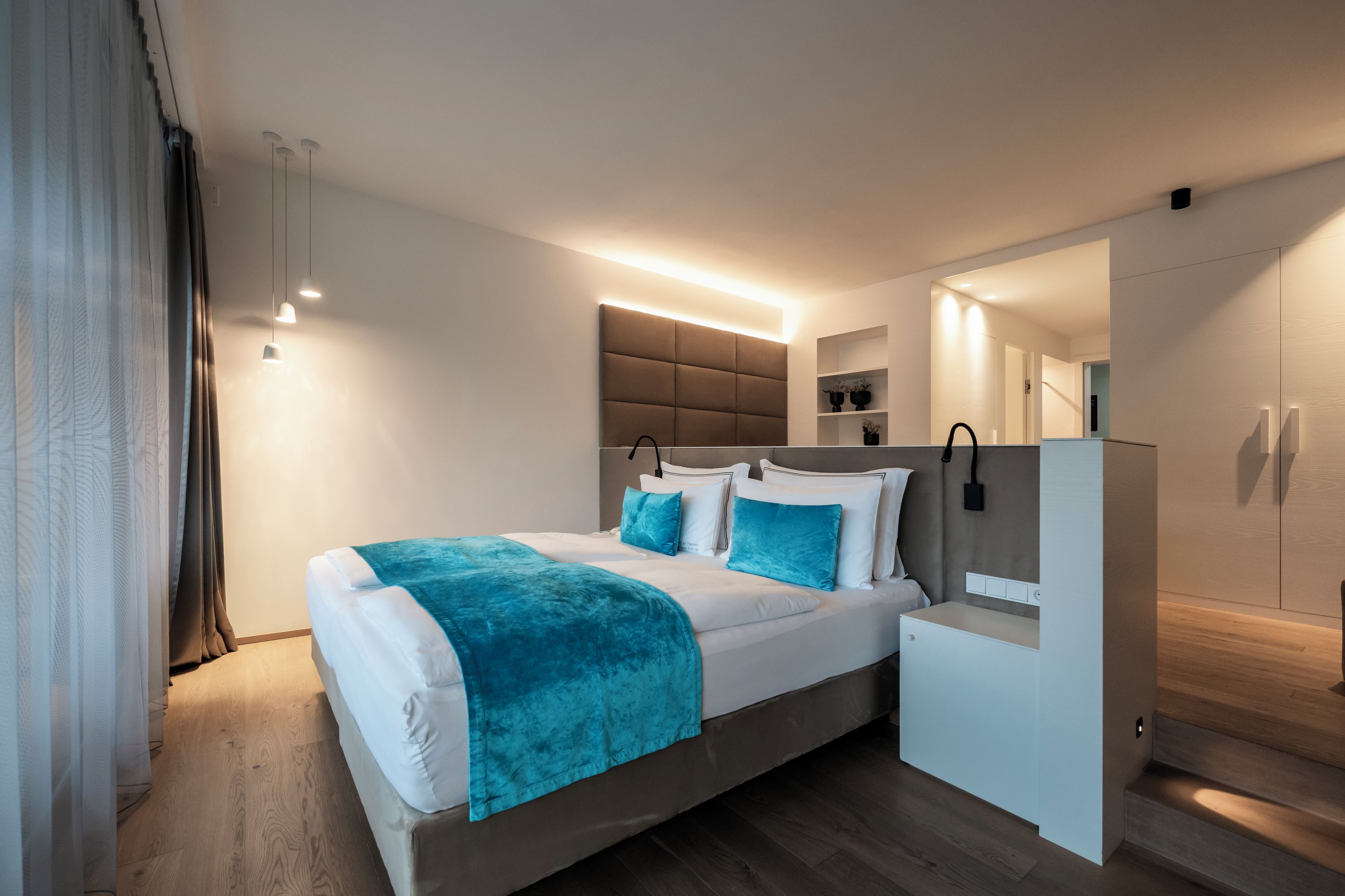 A modern bedroom with a bed, bedside tables, a built-in wardrobe, and a mirror.