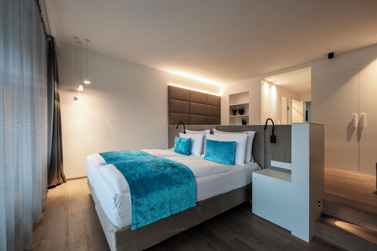 A modern bedroom with a bed, bedside tables, a built-in wardrobe, and a mirror.