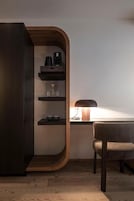 Una habitación moderna con un mueble de madera curvada, un escritorio con lámpara y una silla.