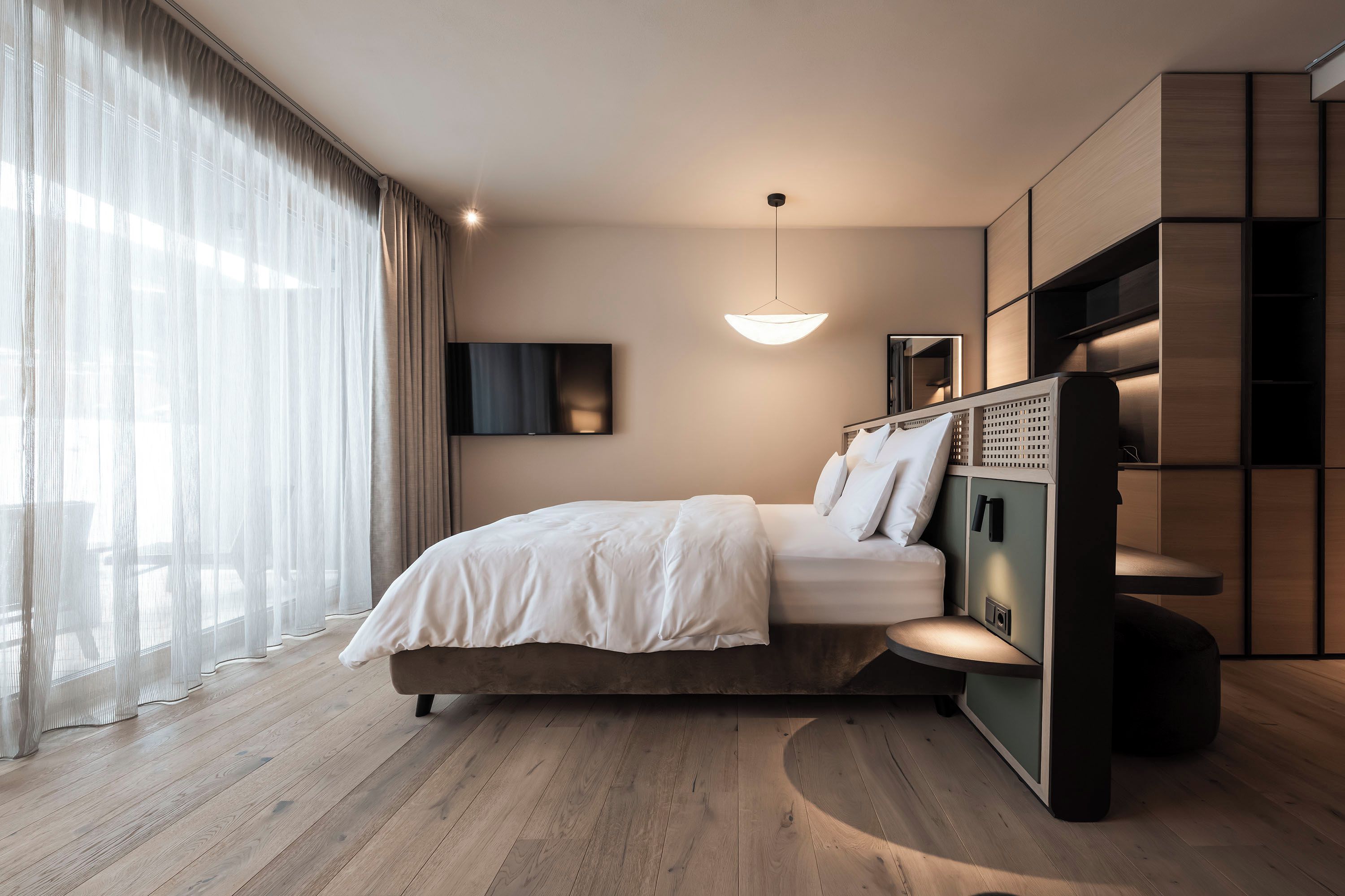 A modern bedroom with a bed, a TV, and a unique built-in shelving unit.
