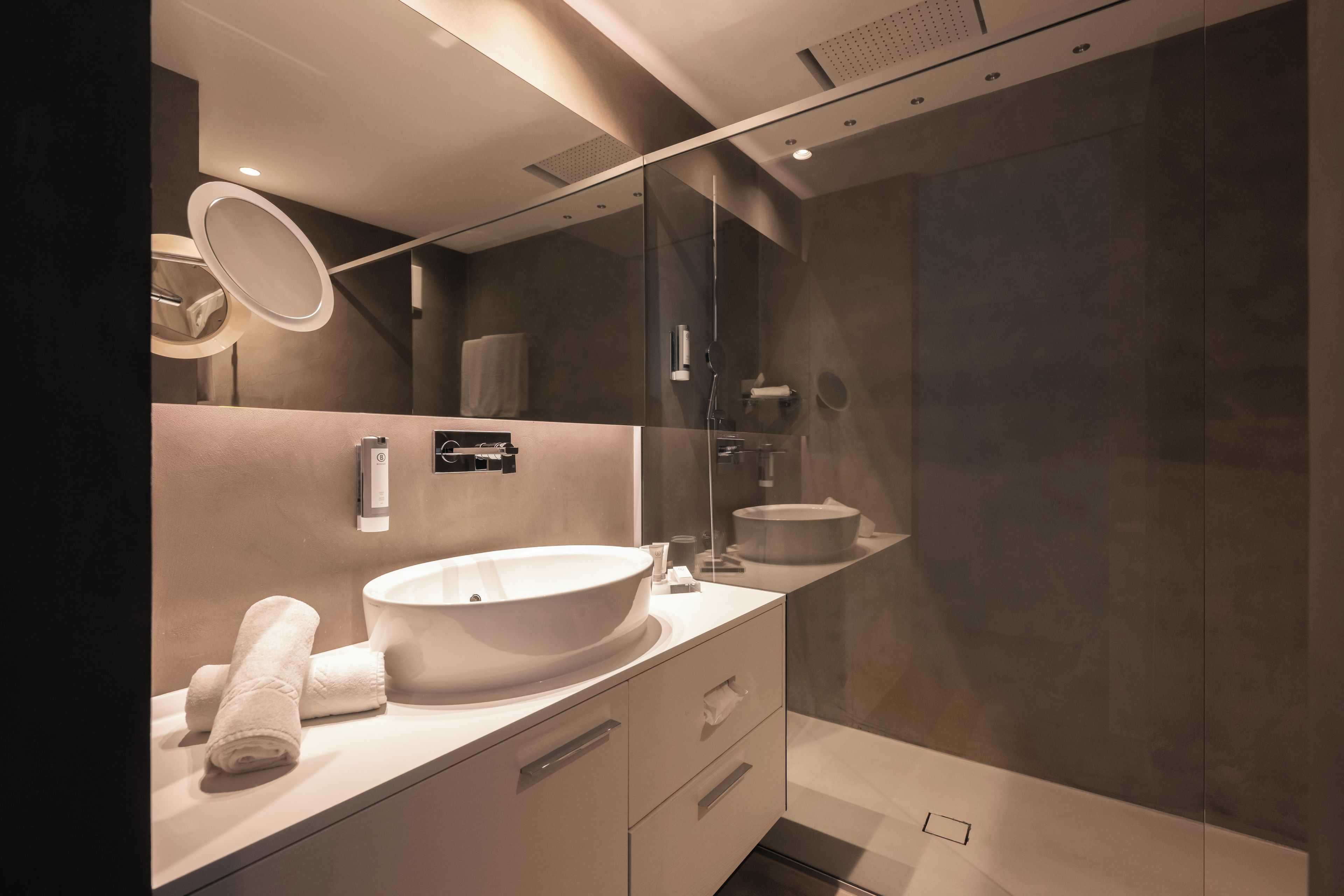 A modern bathroom with a large oval sink, a mirror, and a glass shower enclosure.