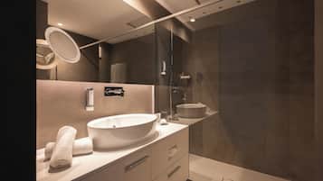 A modern bathroom with a large oval sink, a mirror, and a glass shower enclosure.