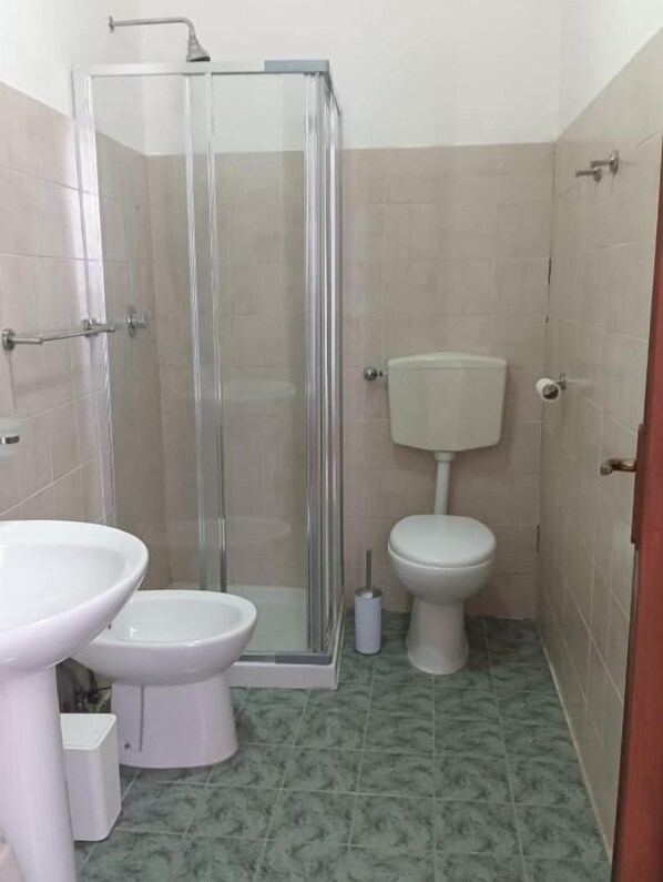 A bathroom with a glass-enclosed shower, a toilet, and a sink.