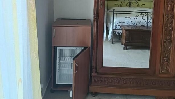 A room with a bed, a wardrobe, a television, and a small refrigerator.