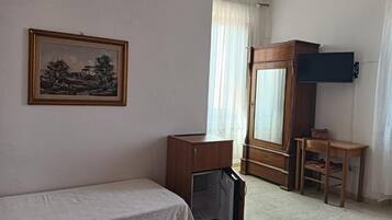 A room with a bed, a wooden cabinet, a television, and a painting on the wall.