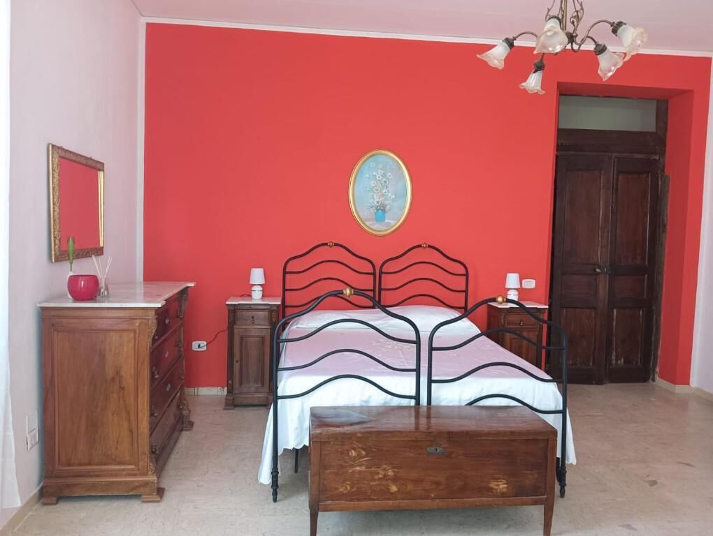 Een slaapkamer met een bed, een dressoir, een nachtkastje en een houten bankje.