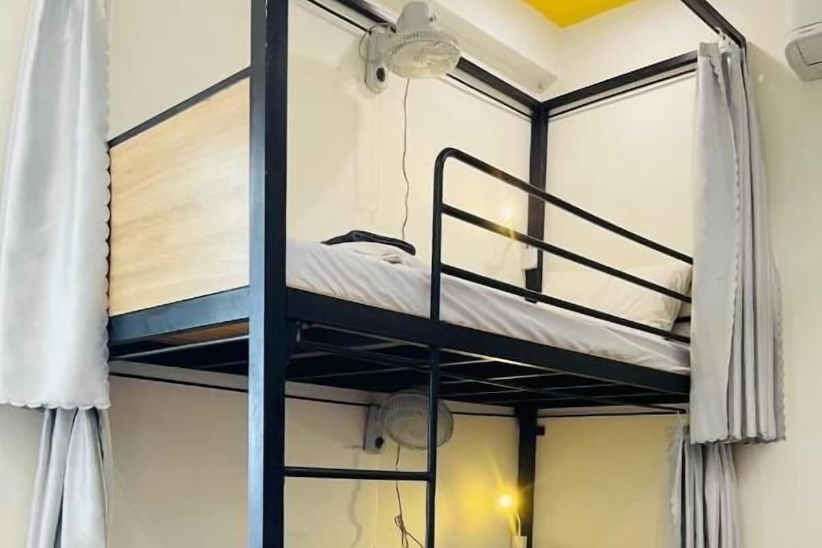 A bunk bed with a desk and a fan, number 8, in a room with wooden flooring.