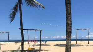 A beach with palm trees, a swing set, and a clear sky.