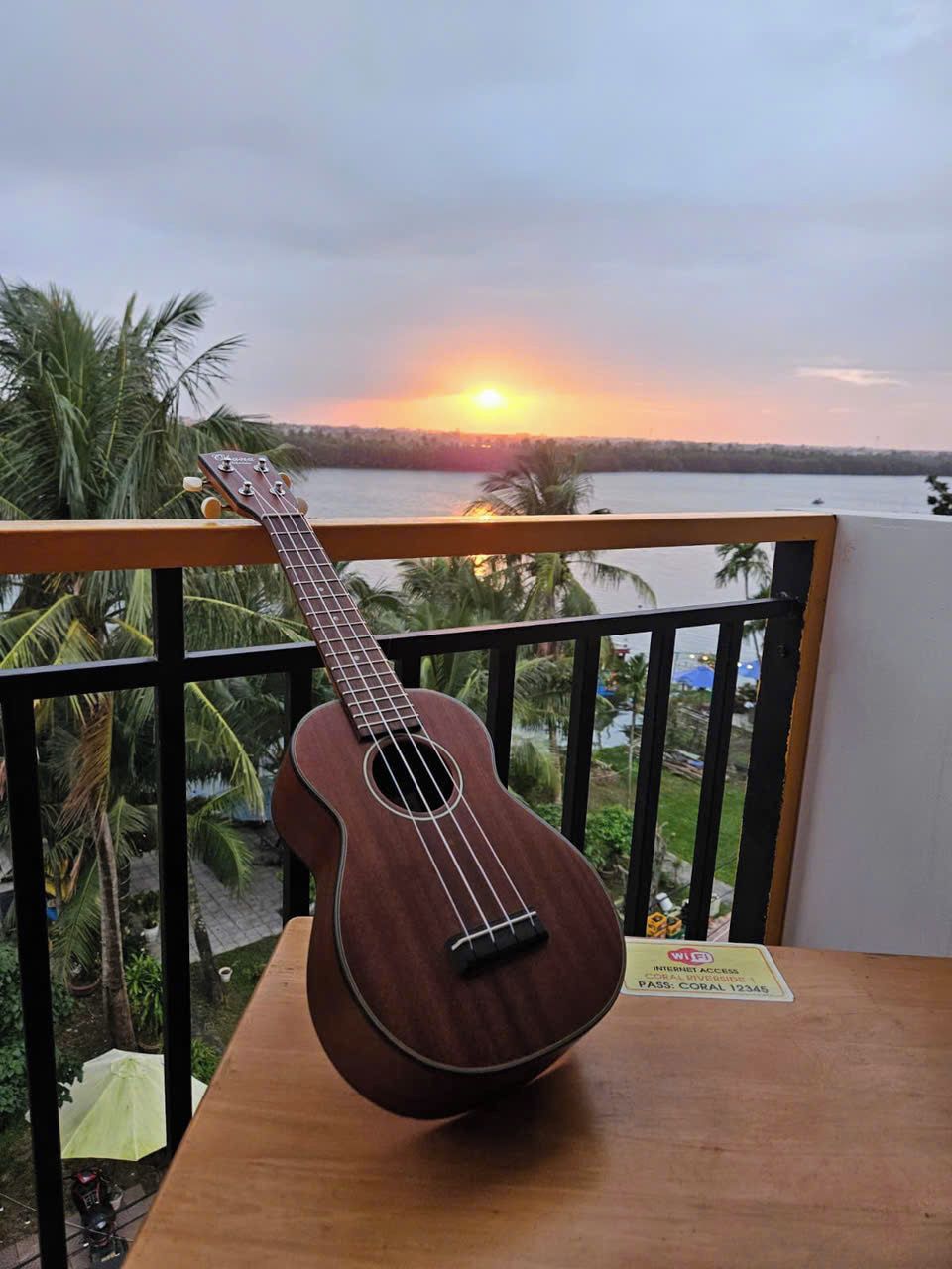 A guitar on a balcony with a sunset view.