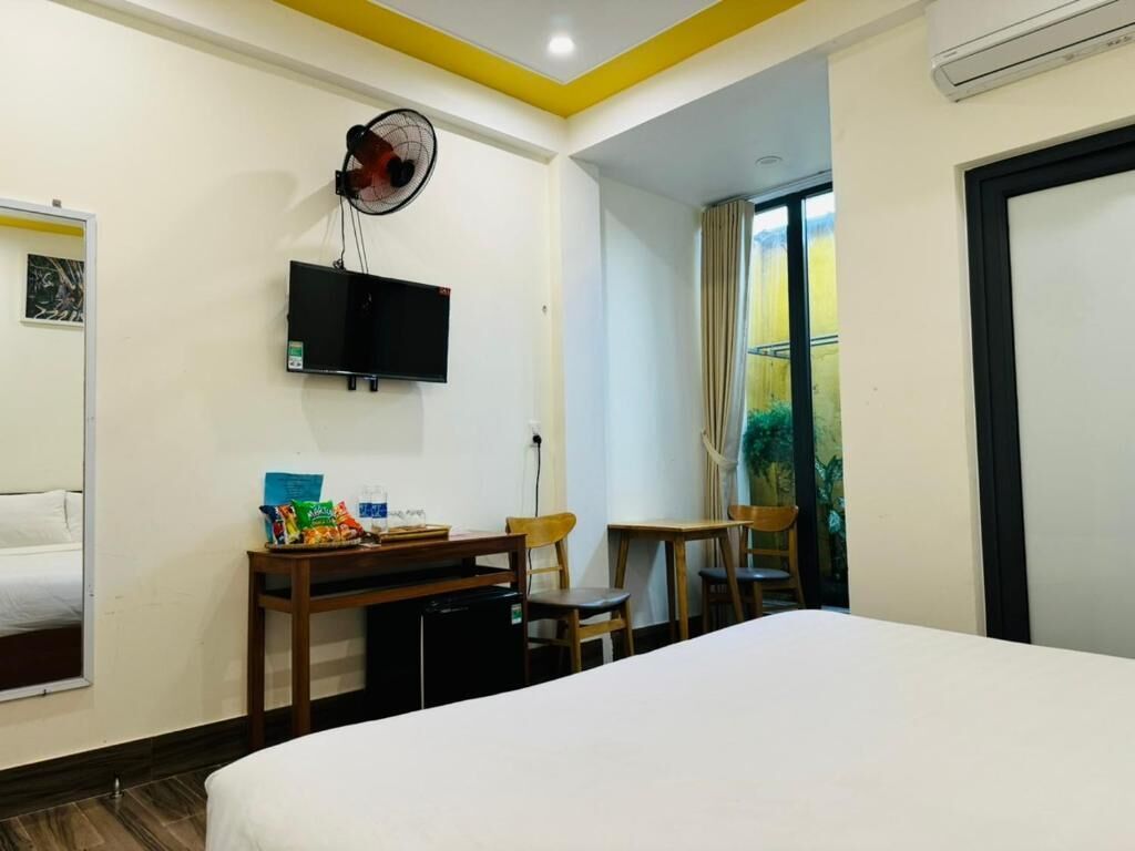 Une chambre d’hôtel comprenant un lit, un bureau avec une chaise, une télévision et un ventilateur.