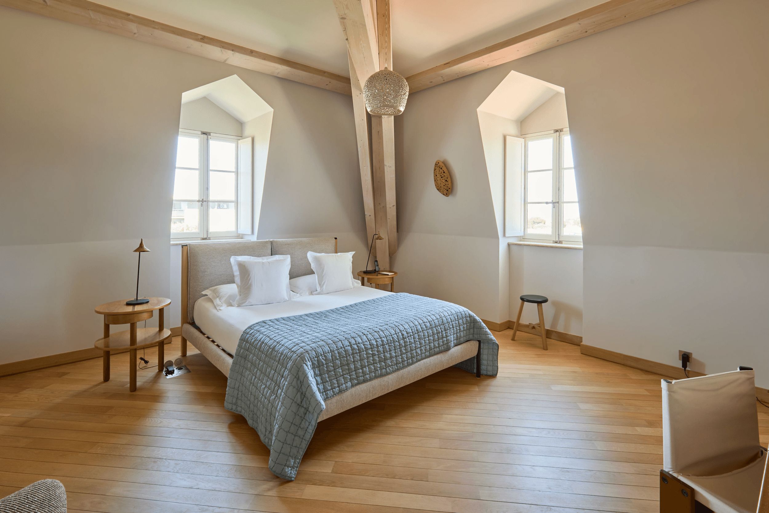 A bedroom with a bed, two bedside tables, a chair, and a window.