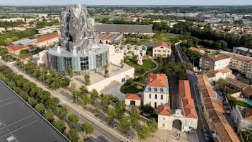 Un bâtiment moderne doté d’une architecture originale, entouré d’un mélange de constructions traditionnelles et modernes, et offrant une vue dégagée sur le paysage urbain environnant.