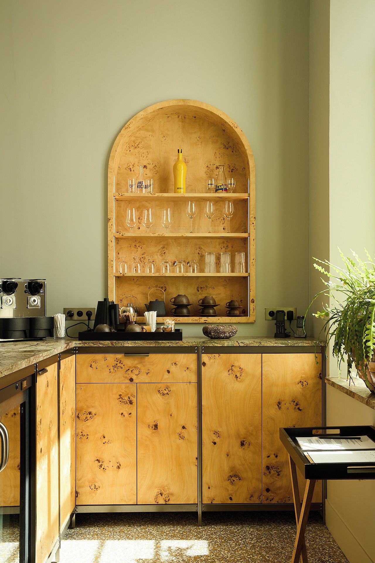 A kitchen with wooden cabinets, a built-in wine rack, and a coffee machine.