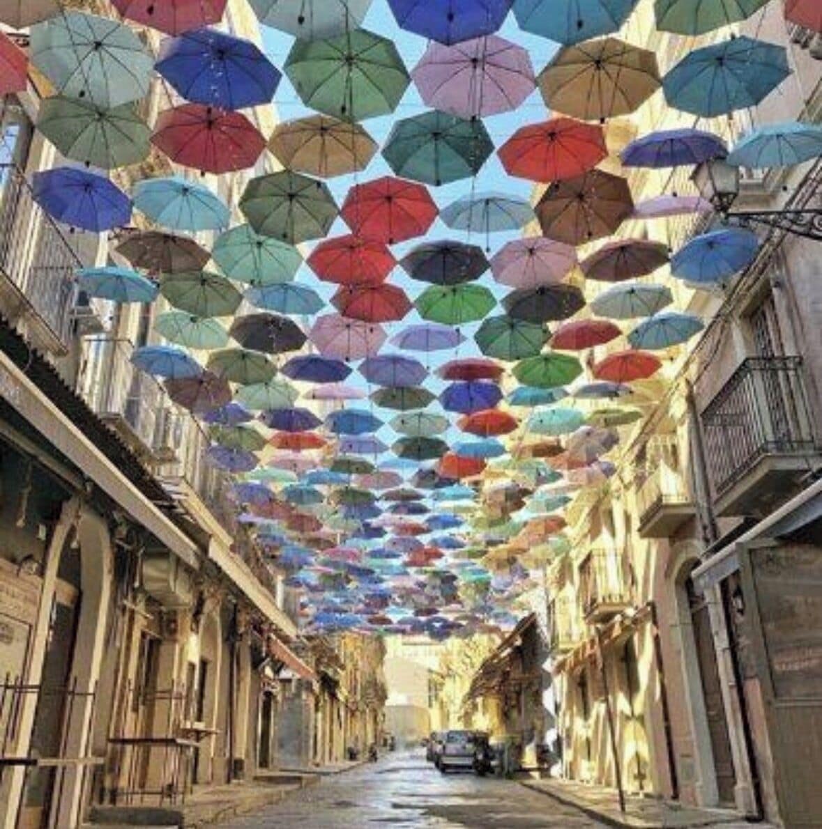 A street lined with buildings, covered by a canopy of umbrellas.