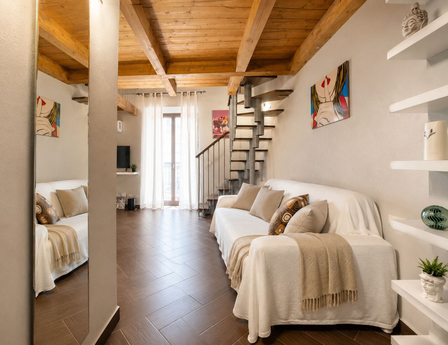 A modern interior with a wooden ceiling, a staircase, and a sofa with decorative pillows.