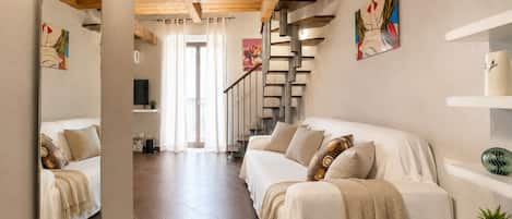 A modern interior with a wooden ceiling, a staircase, and a sofa with decorative pillows.
