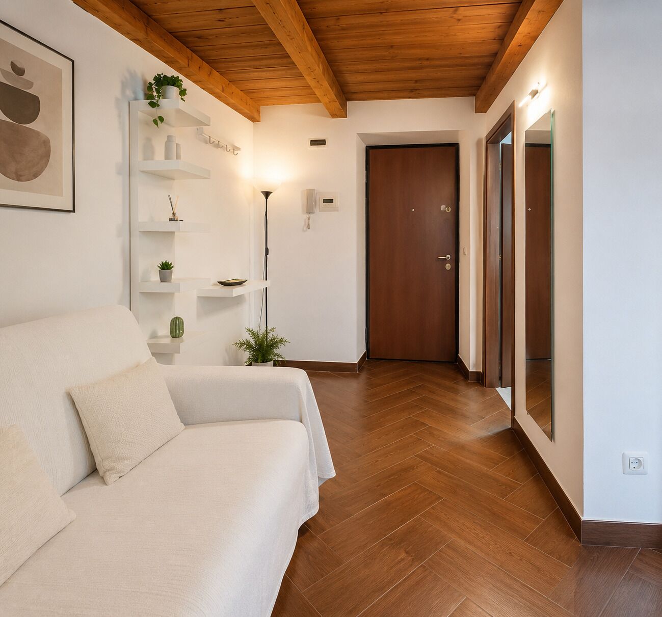 Un interno moderno con un divano, pavimento in legno, una porta e una mensola a parete con piante.