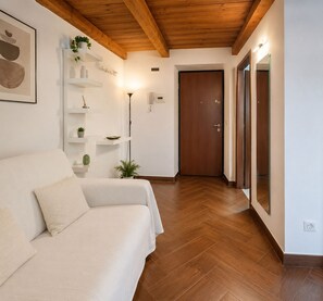 A modern interior with a sofa, wooden flooring, a door, and a wall-mounted shelf with plants.
