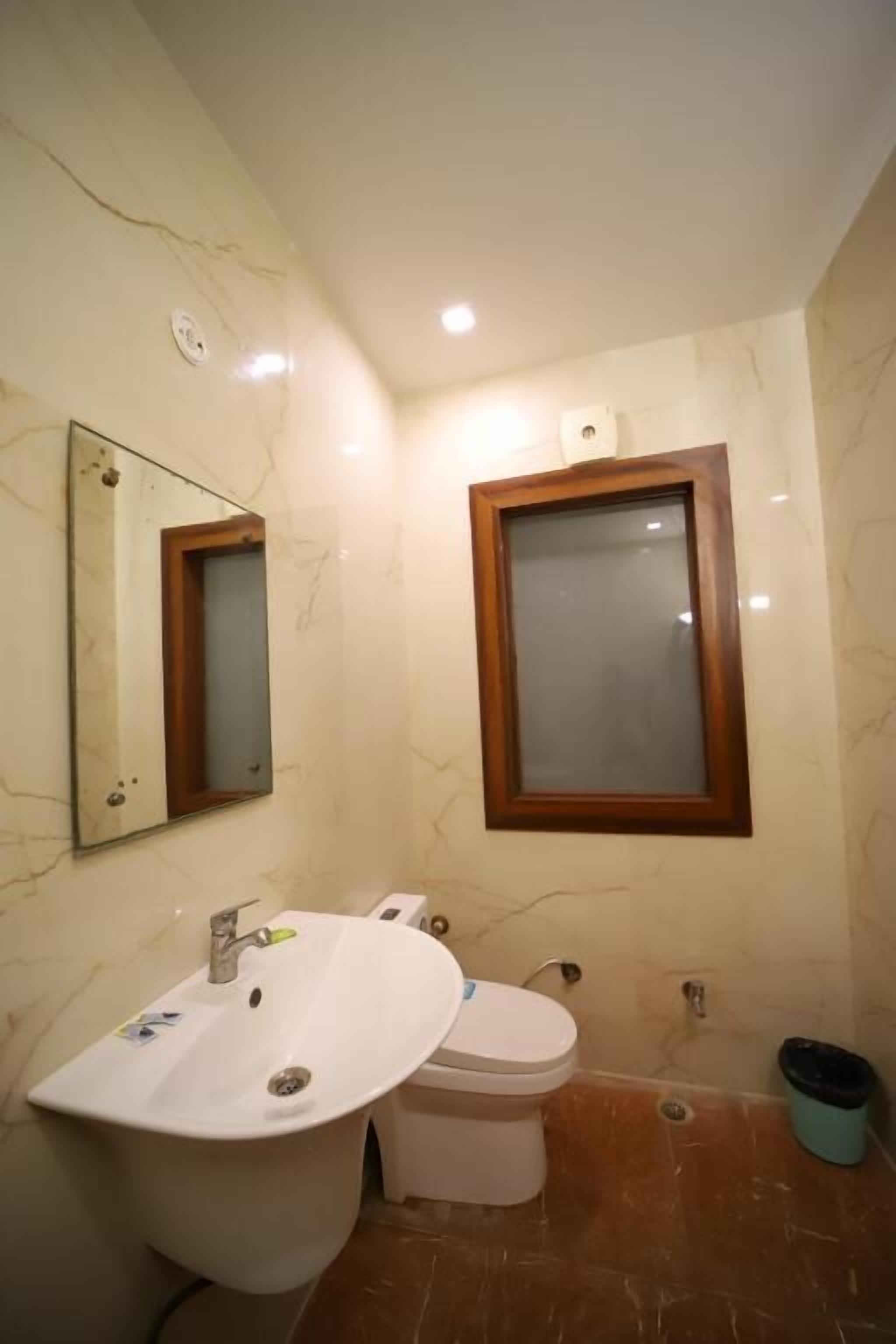 Une salle de bain avec un lavabo blanc, des toilettes et un miroir doté d’un cadre en bois.