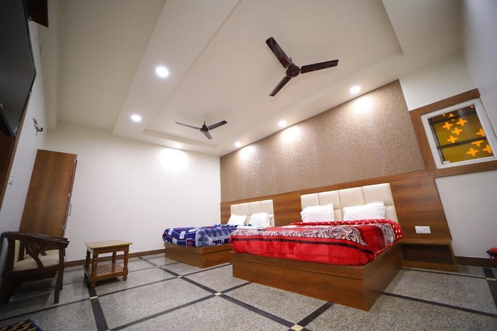 Habitación de hotel con dos camas, ventiladores de techo y una pequeña mesa.