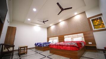 Habitación de hotel con dos camas, ventiladores de techo y una pequeña mesa.