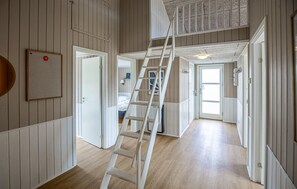 A multi-level interior with a wooden floor, white walls, and a white ladder.