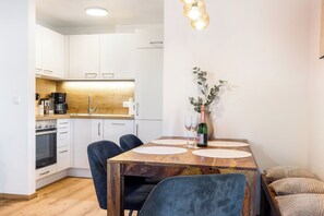 A modern kitchen with white cabinets, a wooden countertop, and a dining area with a wooden table and chairs.