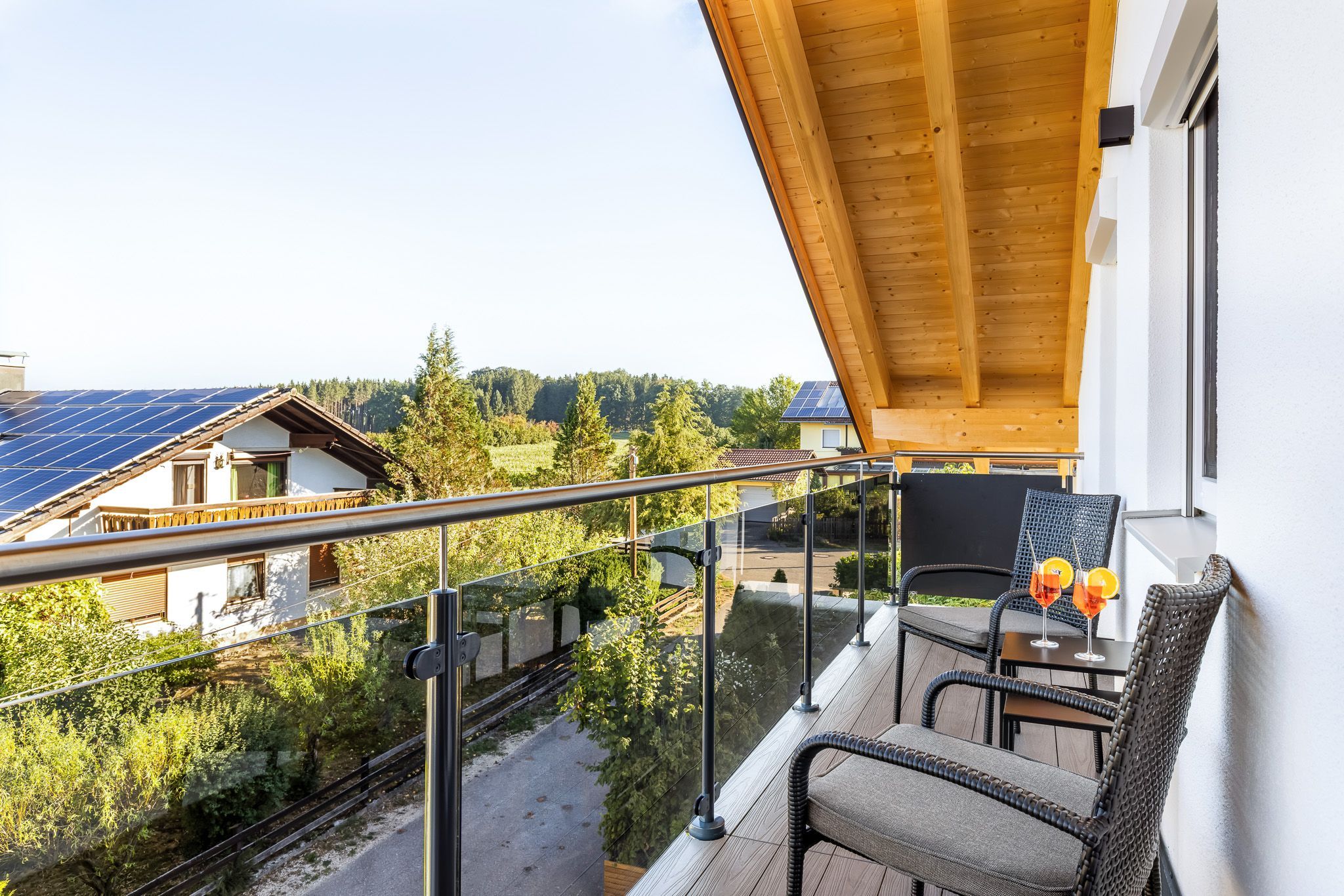 Un balcon donnant sur des panneaux solaires, un coin repas avec des chaises et une table, et un plafond en bois.