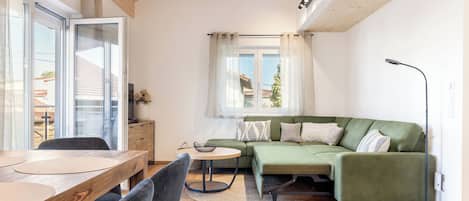 Una sala de estar moderna con una mesa de comedor de madera, un sofá verde y una mesita redonda.