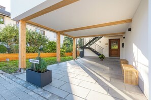 A covered outdoor area with a staircase leading to a door, a planter with greenery, and a bench. - Vacation rental with two separate bedrooms, 62 square meters (Petting)