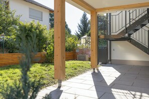 A covered outdoor area with a wooden bench, a metal staircase, and a paved patio.