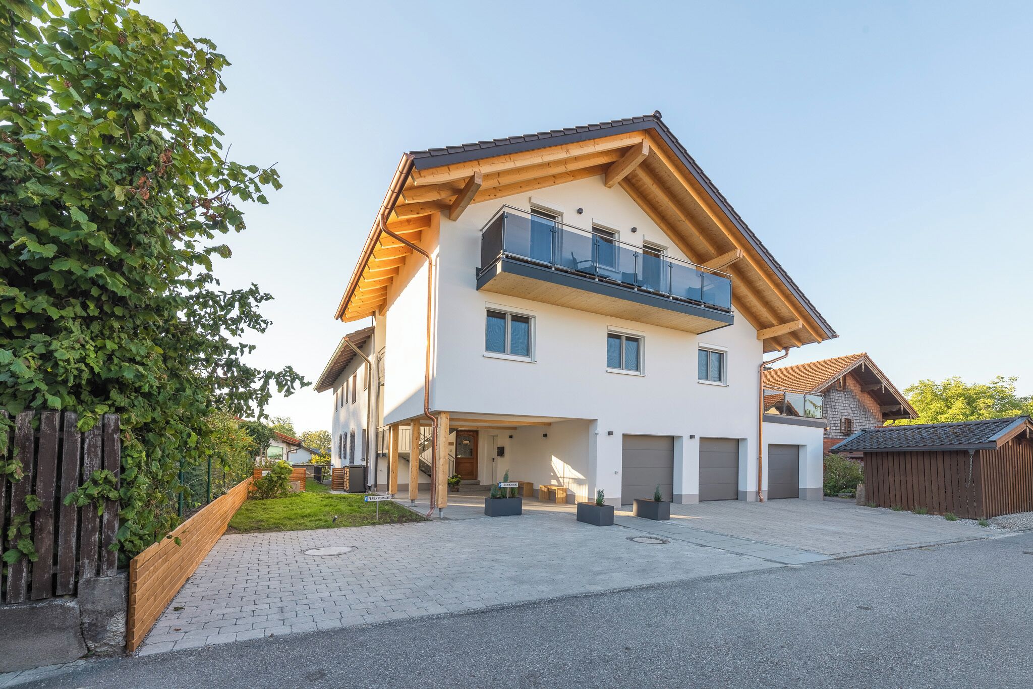 Une maison à deux étages avec un balcon, un garage et une allée pavée.