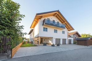 A two-story house with a balcony, a garage, and a paved driveway.