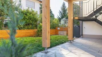 Un espacio al aire libre techado con un banco de madera, una escalera de metal y suelo pavimentado.