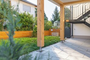 A covered outdoor area with a wooden bench, a metal staircase, and a paved floor.