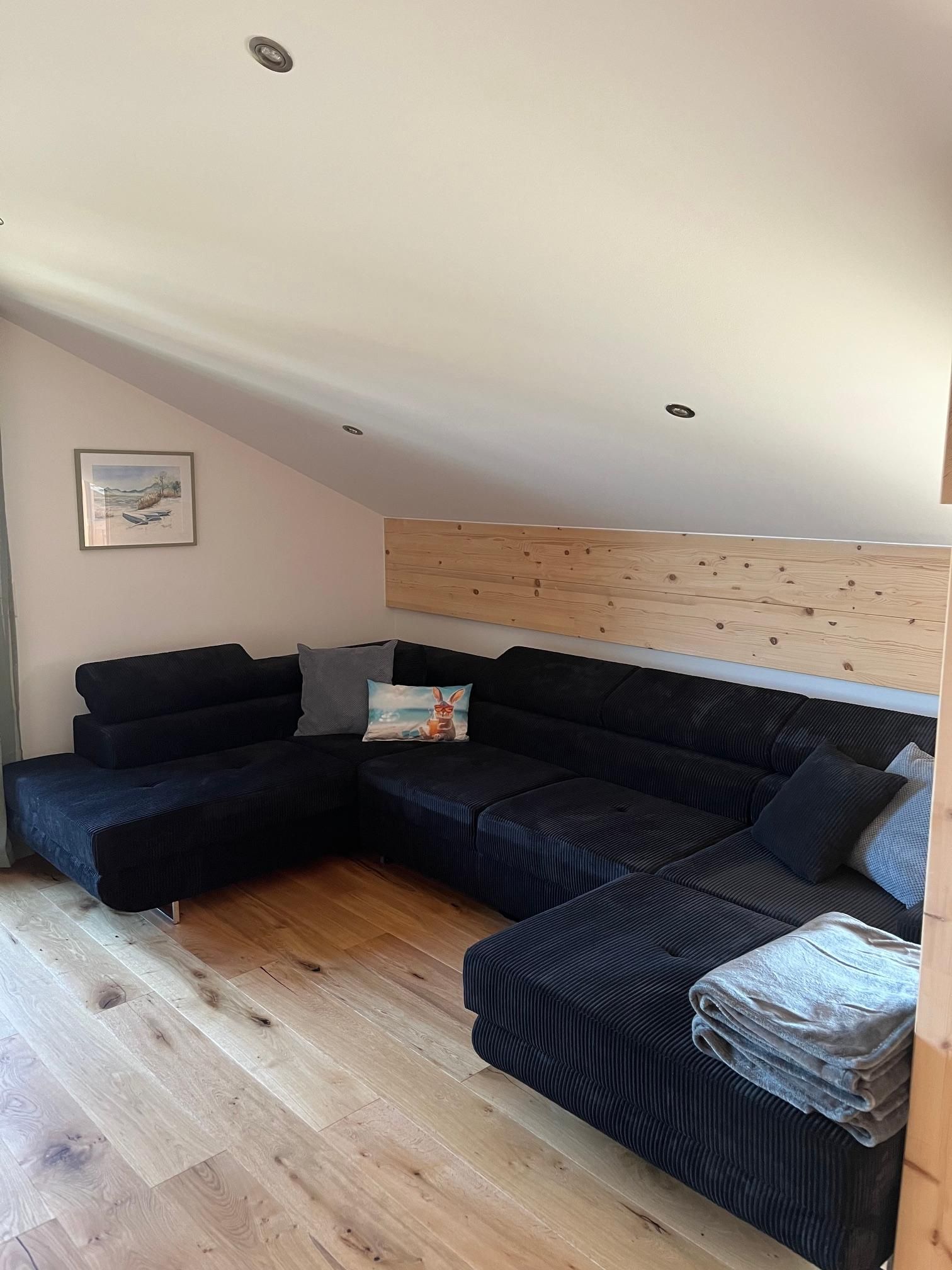 Un soggiorno moderno con un divano componibile, una testiera in legno e un quadro incorniciato appeso al muro.