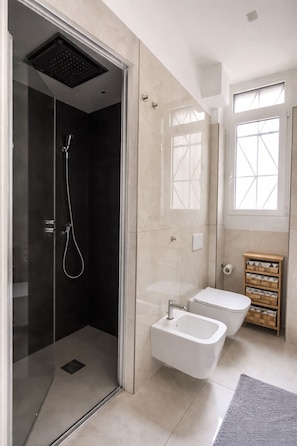 A modern bathroom with a glass-enclosed shower, a white sink, and a wooden storage unit. - Peace and Quiet: Designer Apartment in Isola, Prime Location in a Lively Neighborhood (Milano)