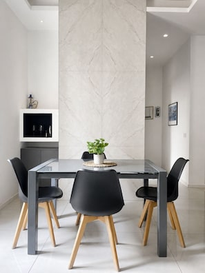 A modern dining room with a glass table, black chairs with wooden legs, and a marble wall. - Peace and Quiet: Designer Apartment in Isola, Prime Location in a Lively Neighborhood (Milano)