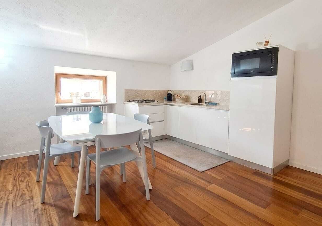 A compact kitchen with white cabinets, a microwave, and a gas stove.